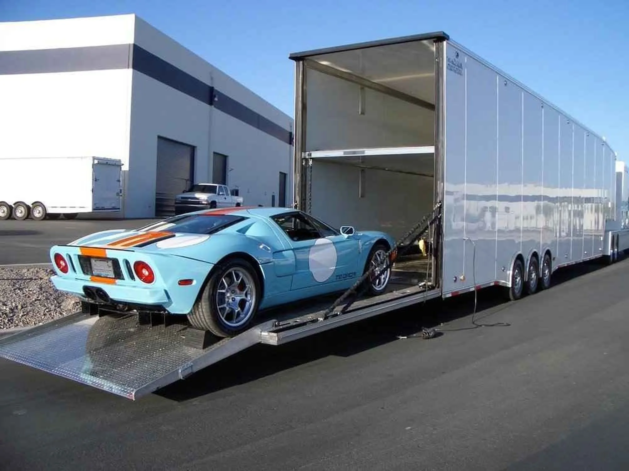 A Light Blue Luxury Car Being Driven Into an Enclosed Trailer