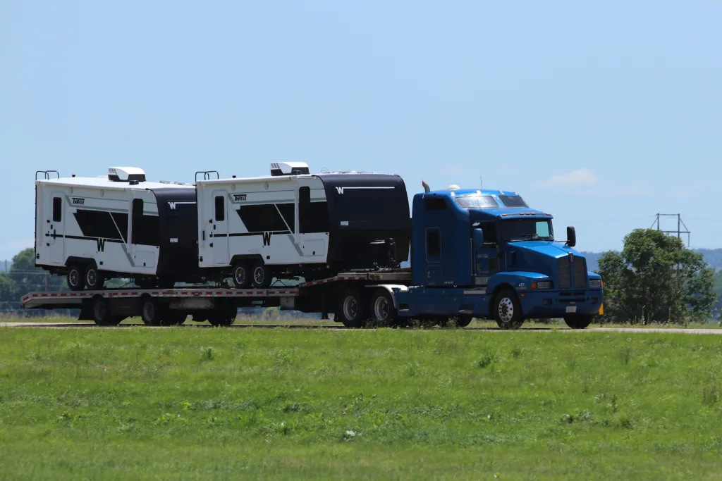 Blue Flatbed Truck Transporting Two Camper Trailers