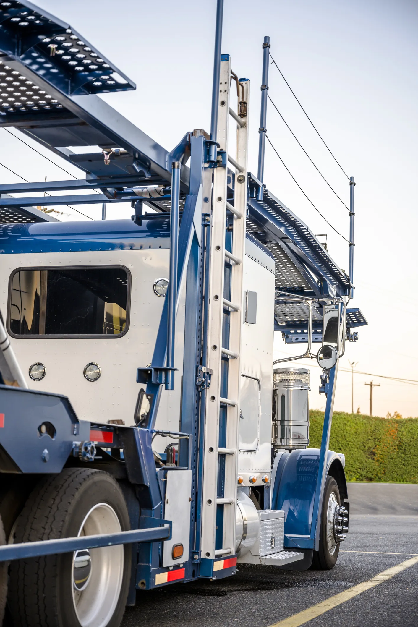 Big rig industrial grade car hauler American bonnet semi truck with empty semi trailer stands on the truck stop parking lot waiting for continue go to the vehicle loading point for next delivery