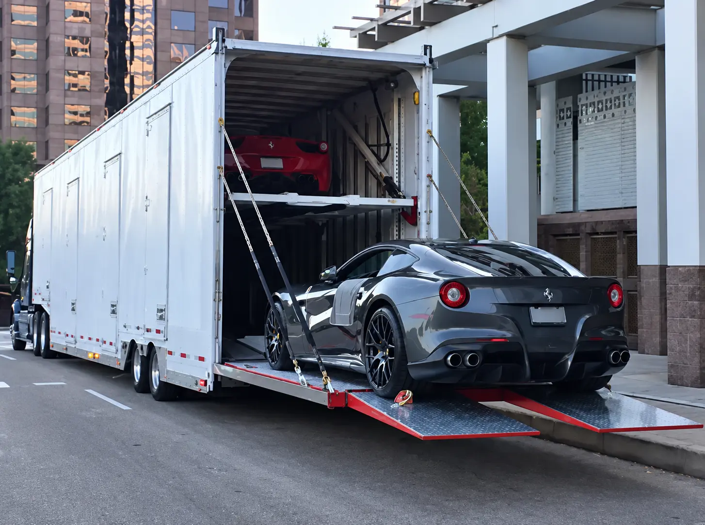Gray Ferrari being loaded into an enclosed car transport trailer.